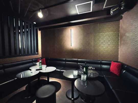 船橋プライマル夜営業の店内。黒いソファと丸テーブル、赤いクッション